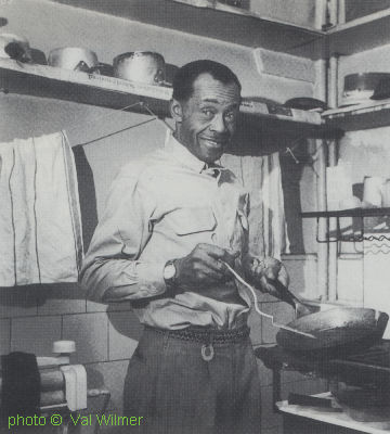 Jesse Fuller cooking breakfast in Streatham, London, UK (at Val Wilmers' then home), 1960; source: Val Wilmer: Mama Said There'd Be Days Like This - My Life in the Jazz World.- London (The Women's Press) 1991, photo pages no #; photographer: Val Wilmer