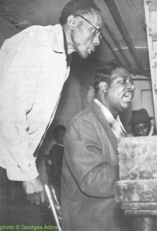 ST.   L O U I S   J i m m y & Otis Spann in Muddy Waters' basement in Chicago, IL, Nov. 1959; in the background (with his hat on): Otis 'Big Smokey' Smothers; source: Rhythm & Blues Panorama No. 30 (1964), p. 48 (back cover); photographer: Georges Adins