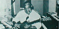 Rooevelt Sykes playing guitar; source: Front cover of 77 LEU 12/50