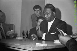 Muddy Waters playing cards with Roger Eagle in the background at the Brazennose Street Twisted Wheel in Manchester, UK; source: https://www.bbc.co.uk/programmes/p01371xt/p013750b: 'Roger, The Eagle Has Landed - A selection of black and white photos by Brian Smith of Roger Eagle from his extensive archive' by Mark Radcliffe; photographer: Brian Smith